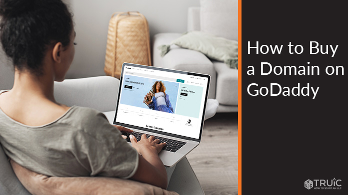 Person on a computer with the GoDaddy homepage on screen.