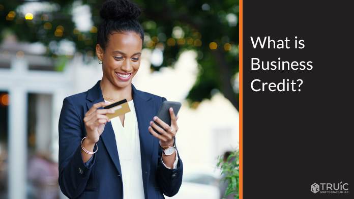 Business woman holding a credit card and looking at a phone.