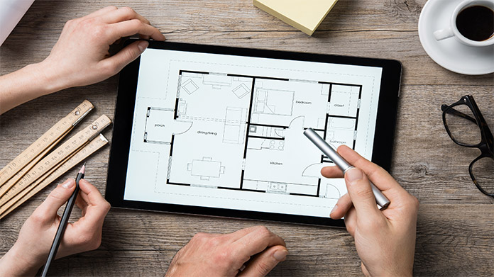 Hands working over a blueprint displayed on a tablet