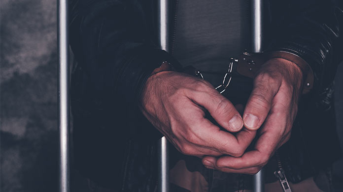 person in a jail cell with handcuffs