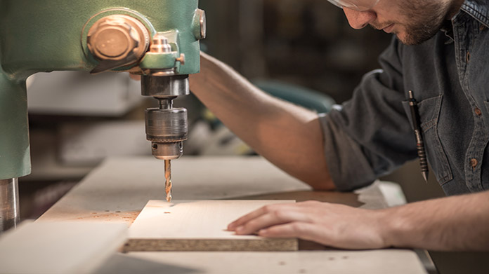 A carpenter drilling a board