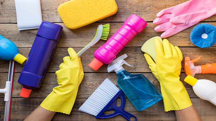 Gloved hands surrounded by cleaning supplies