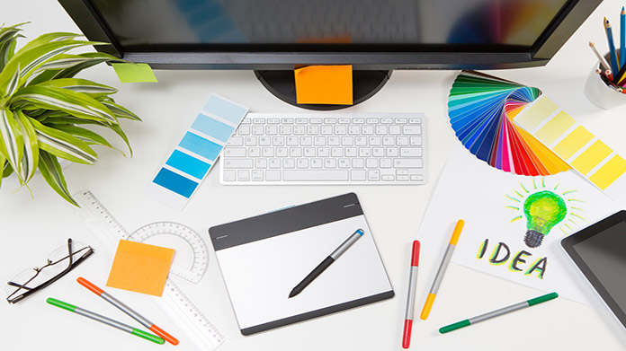 Graphic design tools on a desk in front of a computer