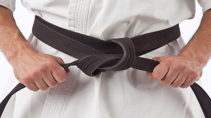 A martial arts belt being tightened