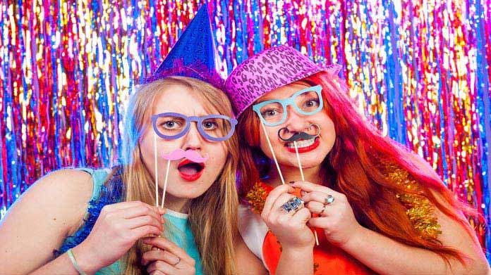 Two girls posing with prop glasses and moustaches