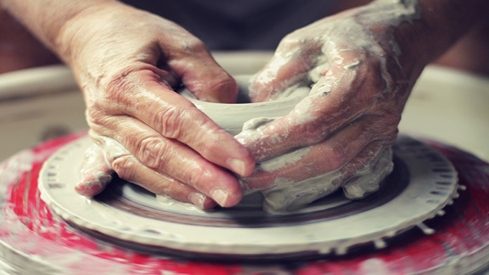person making pottery art on a pottery wheel