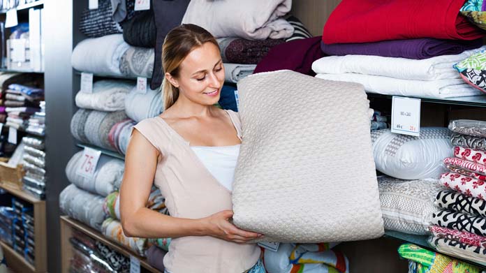 A woman holding a quilt in a store