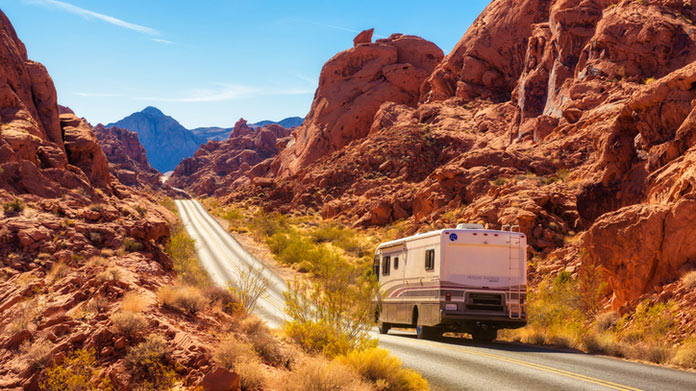A rented RV driving between a canyon