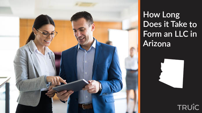 Two looking at a tablet while they work to form an LLC.