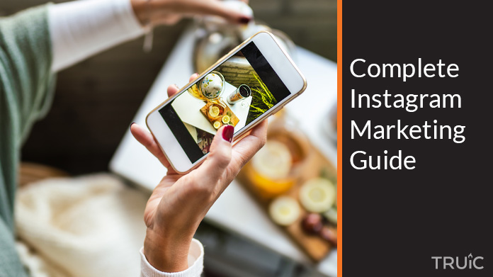 Woman taking pictures for Instagram while refrencing a marketing guide.