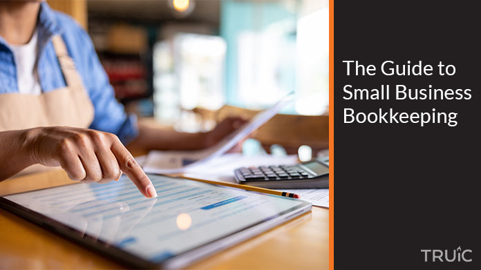 A woman is bookkeeping while using a calculator and a laptop